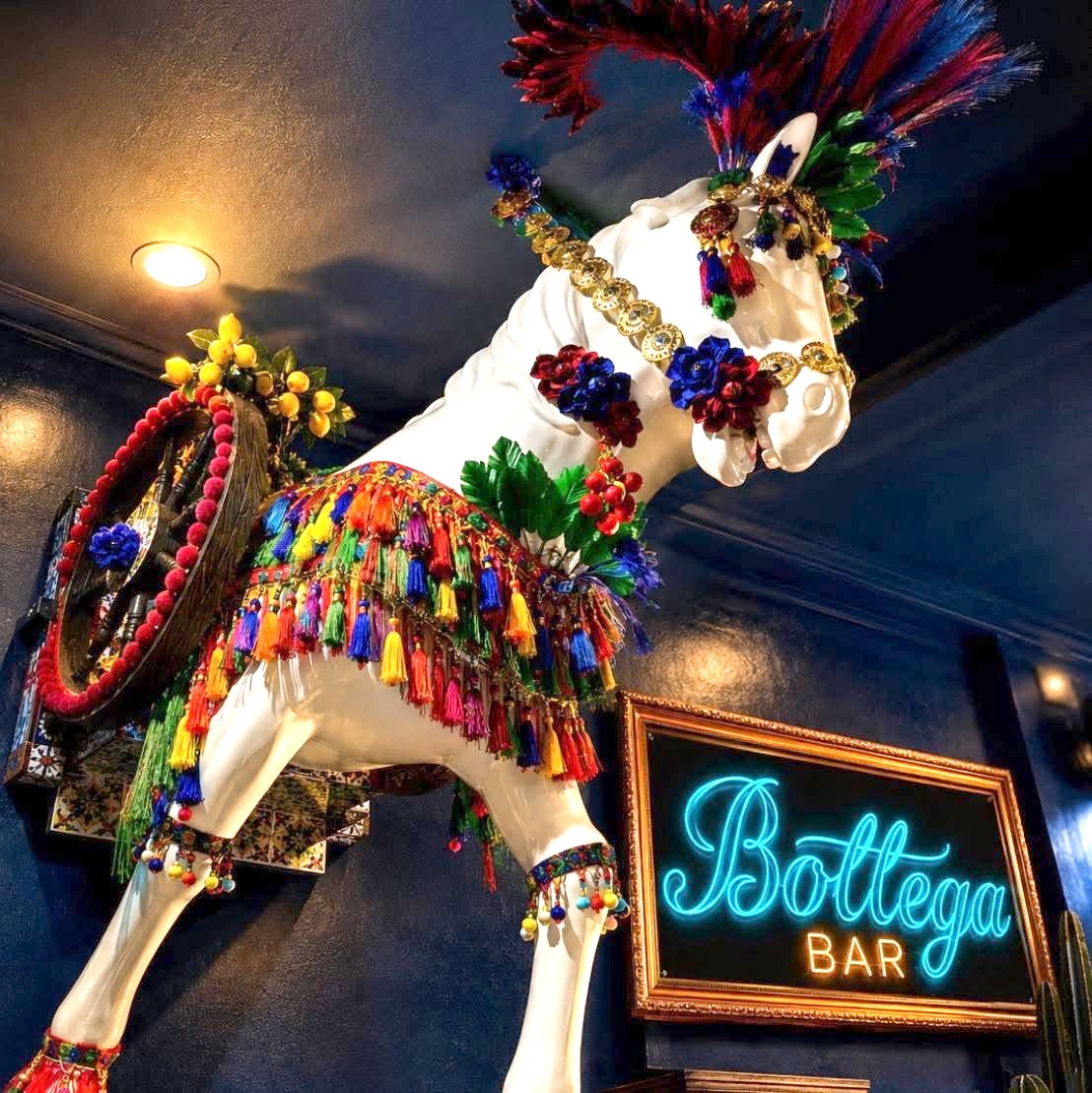 The Bottega Bar carretto horse statue beside the venue's blue neon sign